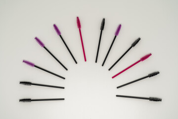 Makeup brushes, eyelash combs and eyebrows on white background with copy space