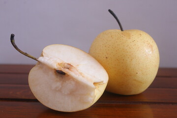 a pear that is placed on a wooden table where the condition of the pear has begun to oxidize, it...