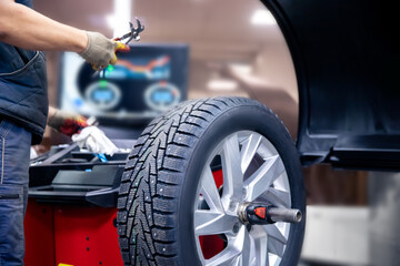 Auto mechanic places weights on steel rim of machine. Concept balancing wheel in car service