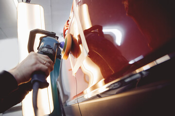 Master mechanic polishes red car with polisher, detailing series