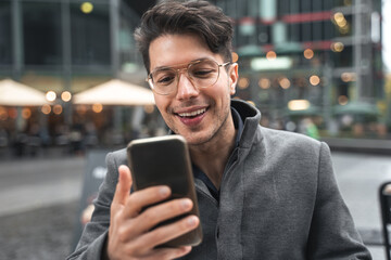 Man sitting at the table and looking at the smartphone screen while having video call