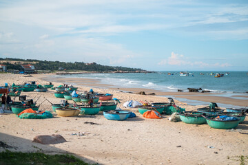 Scenic view of the beach with colourful fishing boats. Blue and green round fishing boats are standing on the sand on the beach in Asia.
