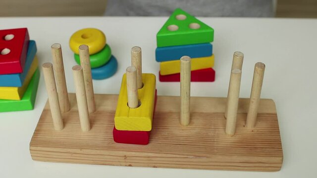 A child playing with a children's educational wooden toy. Preschool education. Study of colors. Montessori concept, early brain exercise. Multicolored logic sorter.