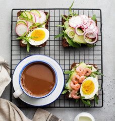 Open sandwiches on dark rye bread with eggs, shrimps, radishes, cucumber, cream cheese and arugula for breakfast. Smorrebrod Traditional dish of Danish cuisine. Top view