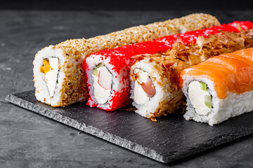 appetizing set of sushi roll on a black stone plate
