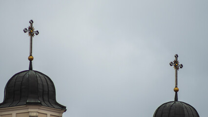 The domes of the Catholic cathedral with crosses on the background of a cloudy sky. Space for text. Worship concept.