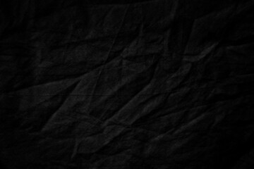 Black burlap cloth texture rough with creases, grungy dark surface background.