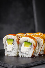 appetizing Philadelphia sushi roll with eel and avocado on a black stone plate
