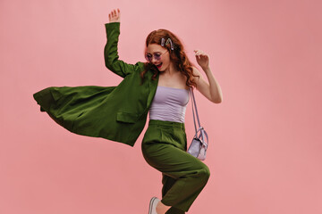 Cute caucasian young girl vigorously posing waving jacket to side in photo studio. Red curly-haired...
