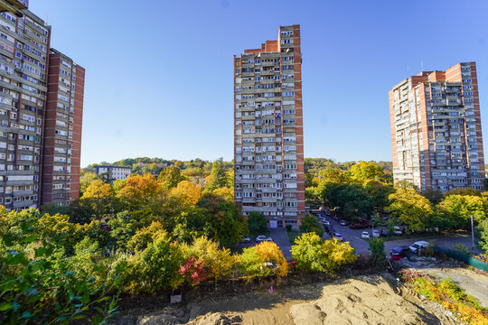 Wide image of the New Belgrade block 4 socialist era buildings during the Autumn with different colors on the trees on the street