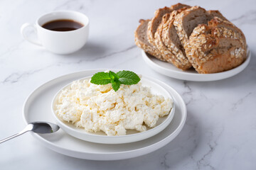 A bowl with fresh cottage cheese, rye bread and coffee on the table. Space for text