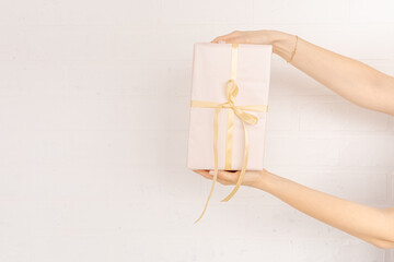 Female hands hold on white background.Gift box wrapped in paper. Gift wrapping tape. Gift concept for Valentine's Day, Women's Day, Christmas, Birthday.