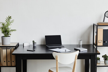 Minimal background image of opened laptop at desk in home office in black and white interior, copy space