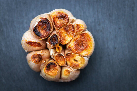 Garlic clove grilled on black stone background; top view.