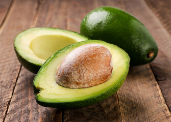 Avocado whole and half on wooden background