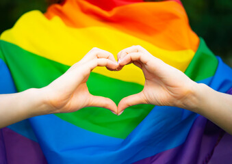 LGBT girl, lesbian woman shows sign in the shape of a heart with her fingers, hands on the...
