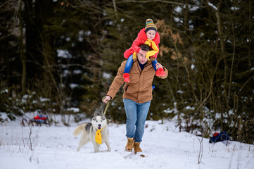 Winter walk, father with daughter and dog in the woods, bright winter clothes.