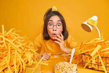 Indoor shot of shocked clever schoolgirl stares bugged eyes cannot believe in amazing relevation...
