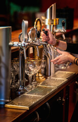 Woman’s hands filling a glass with beer from a tap