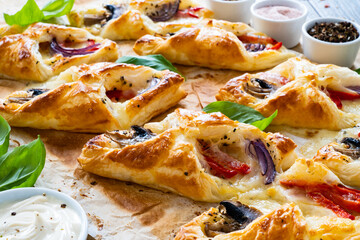 Baked puff pastry with mozzarella, white mushrooms and red bell pepper on baking paper

