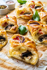 Baked puff pastry with mozzarella, white mushrooms and red bell pepper on baking paper
