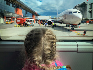 A girl at airport looking at airplane