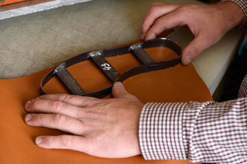 Shoemaker hands putting steel form on leather to make shoe insole on cutting machine in workshop....