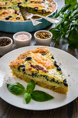 Millet quiche with smoked salmon, spinach and black olives wooden table
