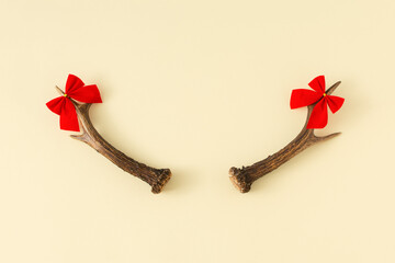 Christmas composition with deer horns with ribbons on yellow pastel background. Copy space. Minimal trendy creative composition.
