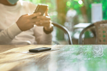 Queue Wireless Calling System Restaurant or Pager Customers System with invoice on table with blur image of man wear protective face mask using cellphone in background. Alarm signal when food is done.