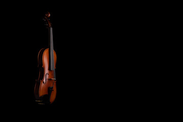 A violin or viola with four strings with a beautiful soft light hitting it on a black background. No.8