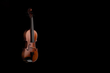 A violin or viola with four strings with a beautiful soft light hitting it on a black background....