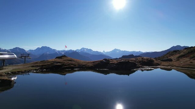 Scenic mountain lake and panorama with swiss flag and gondola station, aerial