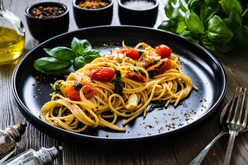 Spaghetti aglio e olio with parmesan, cherry tomatoes and basil on wooden table
