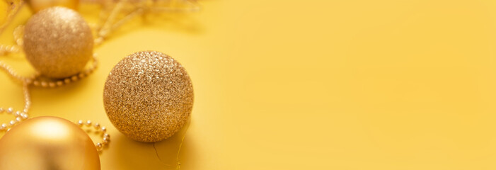 Christmas golden colored decorations on yellow background.