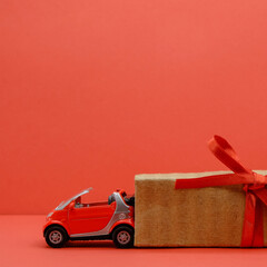Toy red car in a cardboard box with a red bow. Expensive gifts concept. Square image.