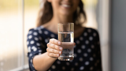 Drinking water. Close up cropped portrait of young lady offer give spectator show to camera cool drink for refreshment. Focus on glass of fresh cold natural mineral or distilled aqua in woman hand