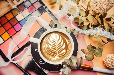 Cup of coffee and eyeshadow on pink background with makeup brushes