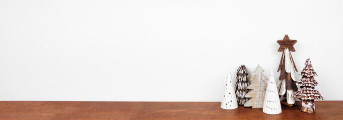 Rustic wooden Christmas tree decor on a wood shelf against a white wall banner background with copy space