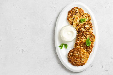 Keto cheesy chicken fritters on white dish with sour cream sauce. Top view, space for text.
