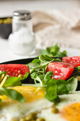 Fried eggs and salad with cherry tomatoes on plate.