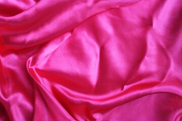 Bright pink satin background. Silk fabric with pleats. Satin, silk or satin create a beautiful drapery. Fashionable design.