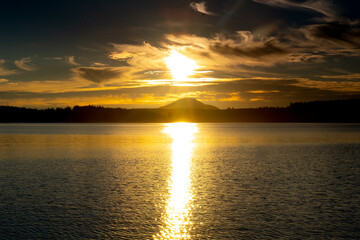 Quinault, WA - USA -Sept. 21, 2021: Horizontal view of the sunset over Lake Quinault Lodge in Olympic National Park. Golden sky with the Sun reflecting on the lake.