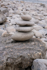 Pyramid of smooth stones on a pebble background. River shoreline in Provence. Vertical image.