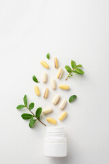Vitamins and herbal supplements in jars with a green plant on a white background with space for text. Biologically active additives.