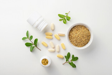 Vitamins and herbal supplements in jars with a green plant on a white background. Biologically active additives.
