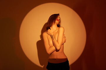 Beautiful girl posing in an orange circle. Shooting topless