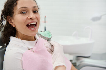 Close-up of dentist hand removing dental impressions of the upper jaw made of silicone material of a woman patient sitting in dentists chair. Dental molds . Imprint of the tooth row of high precision. © Taras Grebinets