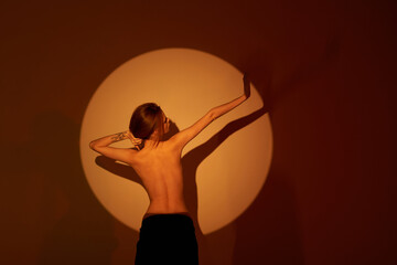 Beautiful girl posing in an orange circle. Shooting topless