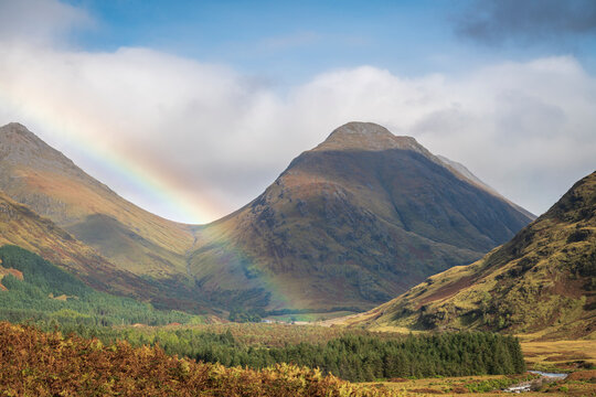 An autumnal 3 shot HDR image of a Rainbow in Glen Etive with Bauchaille etive Mor and Buachaille Etive Beag behind, Scotland. 